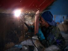 man welding the brown metal board