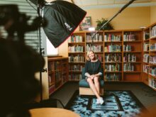 woman sitting on armless chair with light between bookcases in room